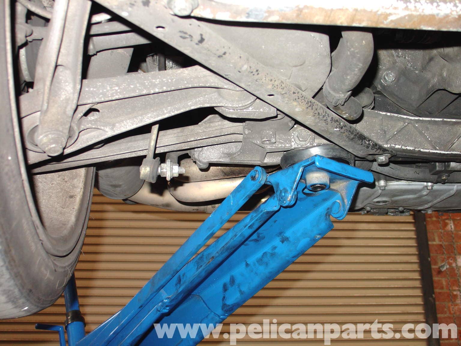 Figure 2: The preferred rear jacking point — the rear suspension mounting point (arrow), which attaches close to the transverse support bar and is very strong. Avoid lifting using any part of the engine.